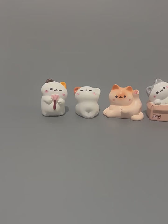 Eight cute cat miniature figurines lined up together on a gray background showing the full collection